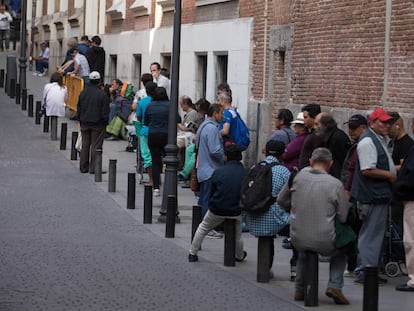 Um grupo de pessoas faz fila para entrar em um refeitório social em Madri