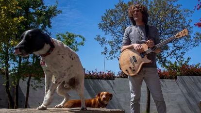 El músico en el jardín de su vivienda en compañía de una de sus guitarras y sus dos perros.