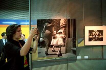 Una mujer hace fotografías en la exposición <i>La condición femenina. España 1950-2000</i>, en la parada de metro de Canal.