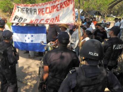 Polic&iacute;as antidisturbios montan guardia mientras un grupo de campesinos abandonan una parcela que hab&iacute;an ocupado al norte de Tegucigalpa.
 