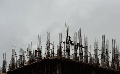 Siluetas de trabajadores con las nubes del monzón muy cerca, en un edificio de gran altura, en el distrito de negocios de Bombay (India).