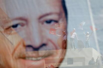 Varias personas participan en un acto electoral junto a un cartel electoral del presidente turco, Recep Tayyip Erdogán, en Sanliurfa (Turquía).