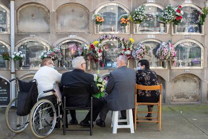 Las flores colman los cementerios de todos los rincones del planeta con motivo del Día de Todos los Santos, que se celebra internacionalmente. En la imagen, una familia deposita las suyas en un nicho en el cementerio del Poblenou (Barcelona), este lunes. Este año no ha habido restricciones de aforo, aunque sí ha sido obligatoria la mascarilla en interiores y en exteriores cuando no fuera posible mantener la distancia de seguridad.