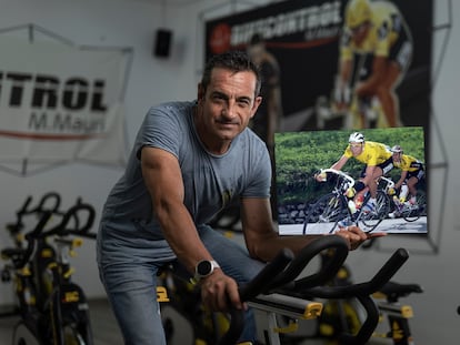 Melcior Mauri, montado en una bicicleta, en la sala Miguel Indurain del Pavellón Deportivo de Calonge, sujeta una foto suya de cuando participó en la Vuelta en 1991.