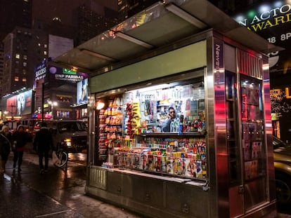 Un hombre habla por teléfono dentro de un kiosco con prensa en Nueva York