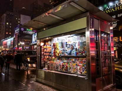 Un hombre habla por tel&eacute;fono dentro de un kiosco con prensa en Nueva York