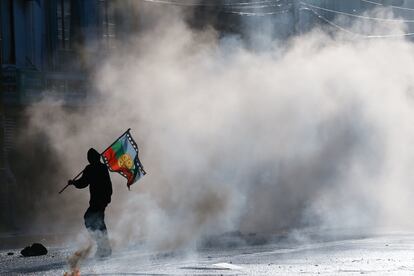 Un manifestante con una bandera mapuche en el medio del gas lacrimógeno.