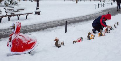 Casi cinco pulgadas (12,7 cm) de nieve cayeron en la región de Boston (EE UU) durante esta noche. En la imagen, Un transeúnte quita la nieve de las estatuas 'Make Way For Ducking' vestidas con capas en los Jardines Públicos de Boston.