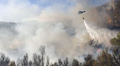 Un helic&oacute;ptero suelta agua sobre un incendio en D&eacute;nia.