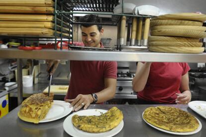 Un camarero corta un trozo de tortilla en la Cervecería Manolo.