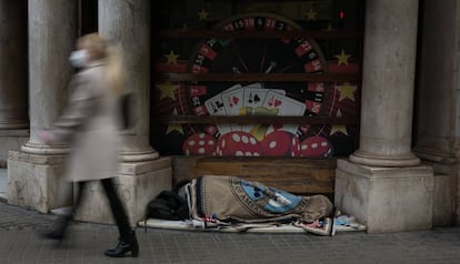 Una persona sin hogar duerme en la entrada de un casino en Barcelona.