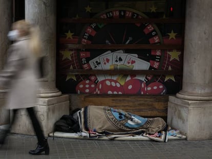 Una persona sin hogar duerme en la entrada de un casino en Barcelona.