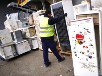 Un operario trabaja en un planta con frigoríficos usados para su reciclaje.