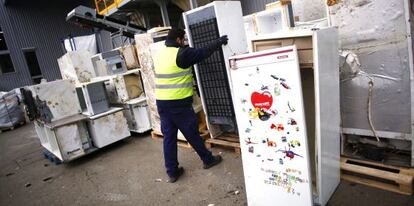 Un operario trabaja en un planta con frigoríficos usados para su reciclaje.