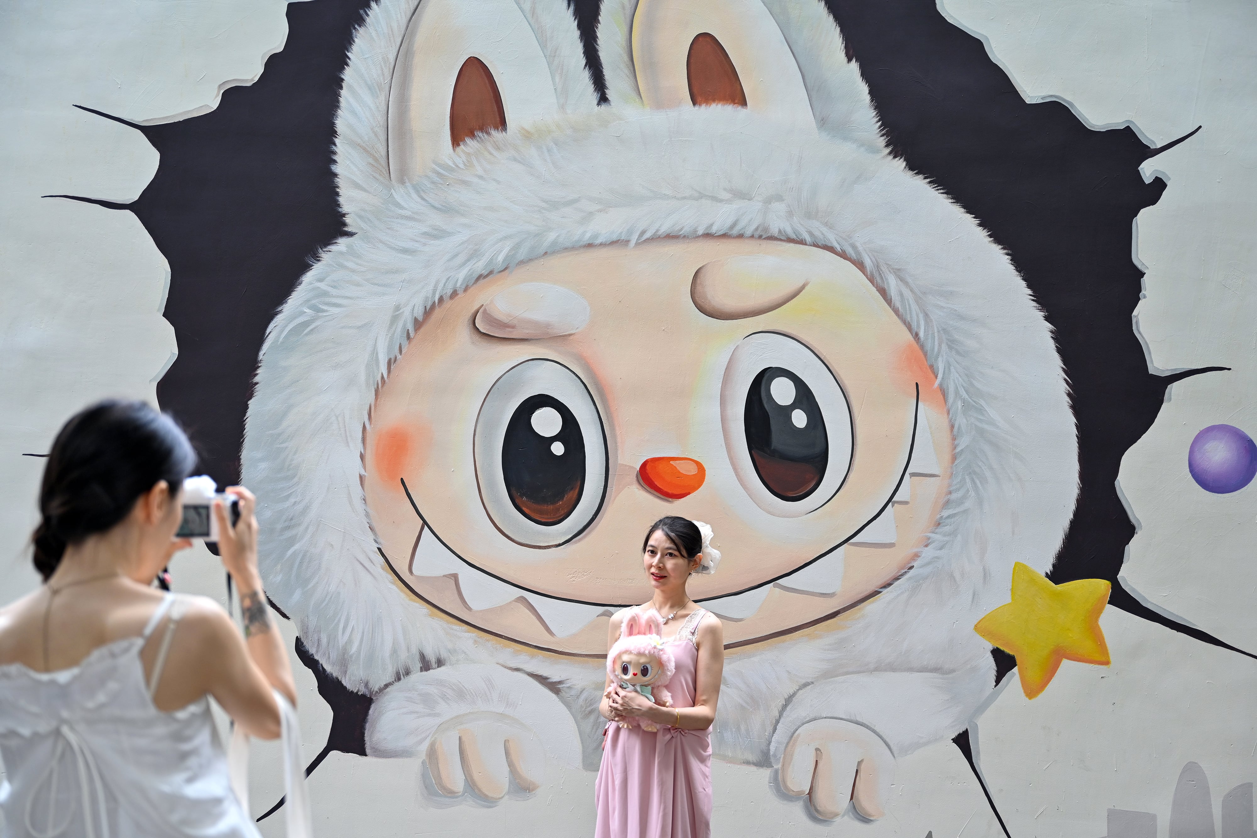 Una mujer posa frente a un grafiti de un Labubu en Chengdu (China) el pasado mes de junio.
