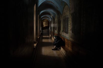 Una peregrina se masajea los pies a las puertas de la iglesia del monasterio.