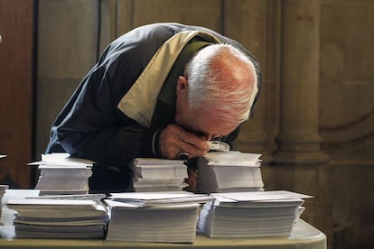 Una persona observa con una lupa las papeletas de los diferentes partidos que concurren a las elecciones al Parlamento Catalan.