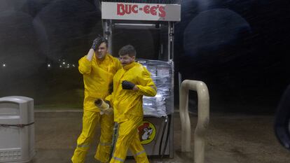 Blake Charanza covered his face from the piercing rain due to Hurricane Beryl, after he and Shawn Trent covered a fuel pump at Buc-ee's, in Freeport, Texas on July 8, 2024.