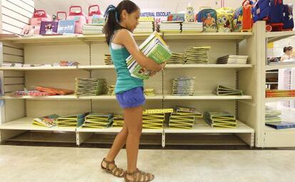 Una niña recoge los libros de texto encargados en un centro comercial de la calle Preciados de Madrid.