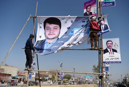 Trabajadores afganos cuelgan una pancarta del candidato Khawja Mahbub Sediqi en una carretera. con motivo de la campaña electoral parlamentaria.