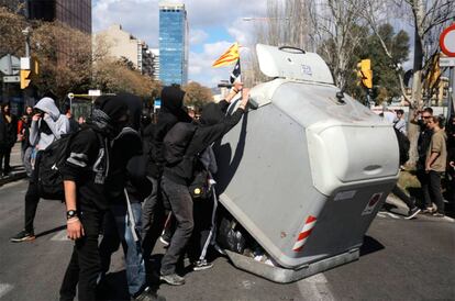 Varios manifestantes vuelcan un contenedor durante el acto de Vox en Barcelona.