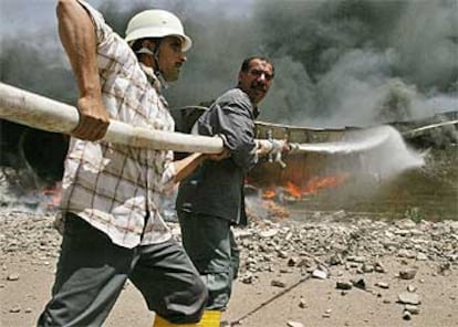 Dos bomberos iraquíes luchan para extinguir un incendio en un depósito de combustible tras un ataque con morteros en Abu Ghraib.