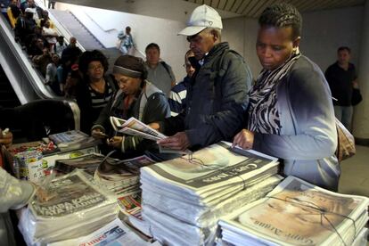 Viajeros se paran a mirar los periódicos que anuncian la muerte de Nelson Mandela en Ciudad del Cabo, 6 de diciembre de 2013.