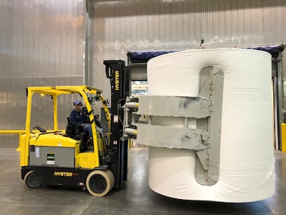 Una elevadora maneja una gran bobina en la fábrica de papel higiénico Charmin. 