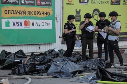 Miembros de la policía ucraniana junto a los cuerpos de las personas asesinadas por el impacto del misil, este viernes. 