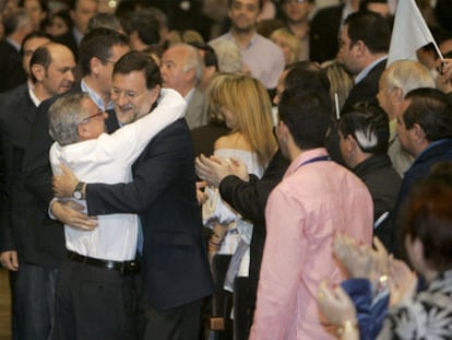 El líder del PP, Mariano Rajoy (2-i), es saludado por un militante del partido a su llegada a un acto para celebrar el primer aniversario de la victoria del partido en las elecciones gallegas