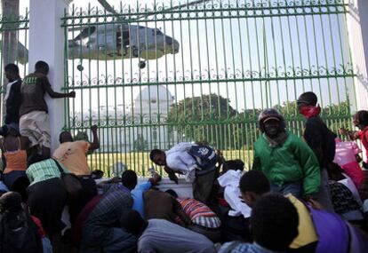 La gente se agolpa fuera de la sede del derruido palacio presidencial, donde han comenzado a aterrizar los helicópteros estadounidenses para entregar la ayuda