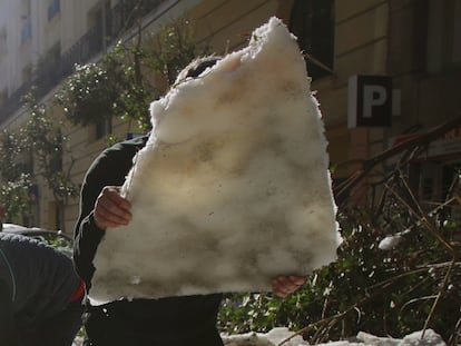 Vecinos retiran con palas el hielo de la calzada en Madrid, tras la borrasca Filomena.