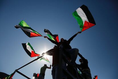 Palestinos ondean banderas durante una marcha en el pueblo cisjordano de Bilin, cerca de Ramala, con motivo del 11º aniversario de su levantamiento en contra de la construcción de la barrera de separación de Israel y la contrucción de asientamientos israelíes.