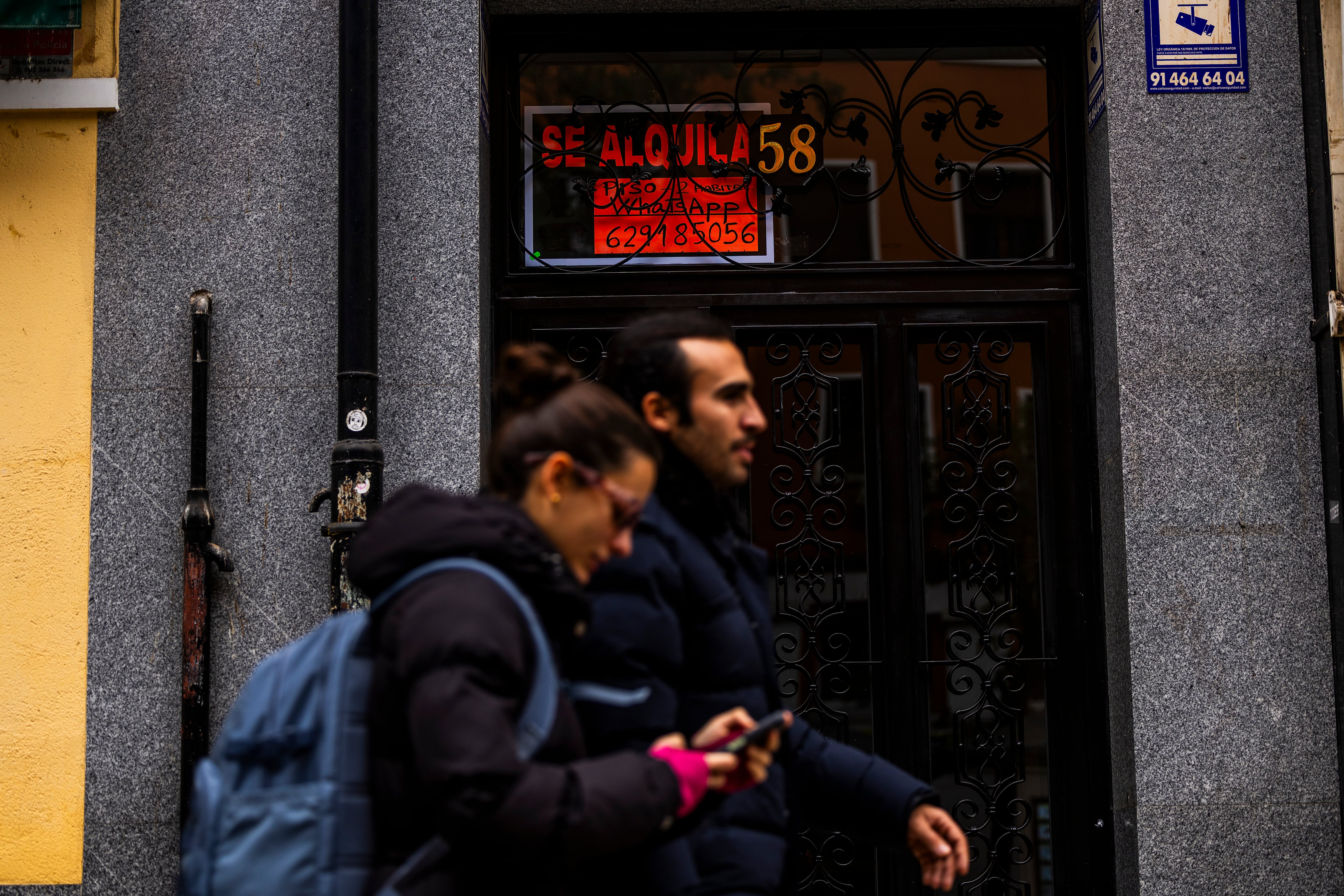 Dos personas pasan por delante de un cartel de alquiler de una vivienda en Madrid.