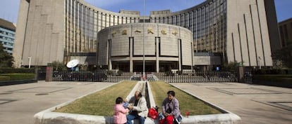 Una familia descansa delante de la sede del Banco Popular de China en Pek&iacute;n (China). 