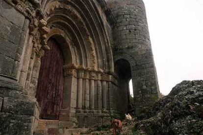 La extraordinaria ermita-fortaleza románica de Santa Cecilia en Vallespinoso de Aguilar se alza sobre una masa de roca, rodeada por un arroyo y campos de trigo.