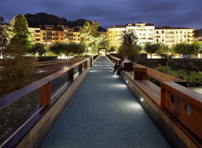 El puente de Arriondas es una pasarela peatonal proyectada por Rogelio Ruiz. Por la noche, su suelo de cristal reciclado parece flotar