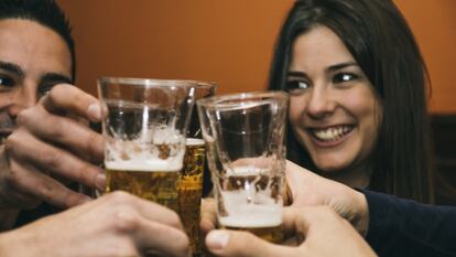 Un grupo de amigos brinda con cervezas en un bar.