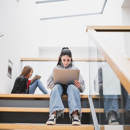 Girls on the high school stairs with laptop and tablet. Digital learning concept.