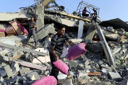 Unos palestinos recuperan algunas de sus pertenencias entre los escombros de su casa en Rafah, destruída en un ataque aéreo israelí contra Gaza. 9 de julio de 2014.