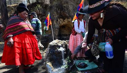 Varias mujeres depositan ofrendas en la piedra tallada de la Curva del Diablo.