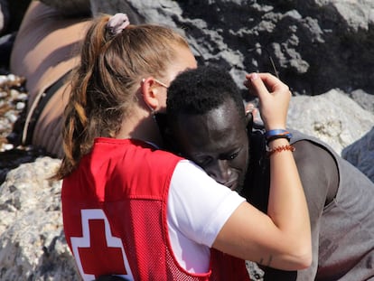 La trabajadora de Cruz Roja abraza al migrante que ha logrado cruzar uno de los espigones fronterizos de Ceuta este martes.