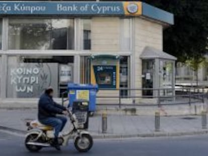 Un hombre circula ayer en motocicleta delante de una sucursal del Banco de Chipre en Nicosia (Chipre).