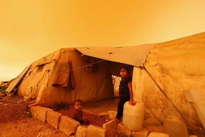 Dos niños se sientan este jueves junto a su tienda de campaña durante una tormenta de polvo sobre la ciudad de Zardana, en el campo de la provincia noroccidental siria de Idlib.
