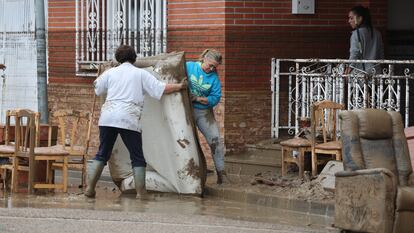 Dos personas sacan material de sus casas tras las inundaciones por la lluvia caída en la localidad toledana de Cobeja.
