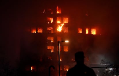 Un agente observa el edificio en llamas.