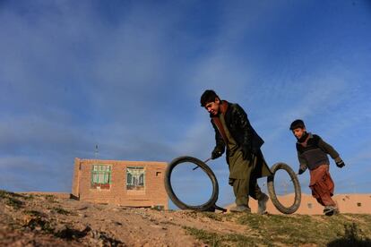 Dos niños afganos juegan con dos llantes en una calle de Herat.