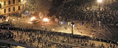 Aspecto de la plaza de la Liberación de El Cairo, la pasada madrugada. Los detractores de Mubarak se refugian detrás de una barricada tras el enfrentamiento a pedradas con los partidarios del 'rais'.