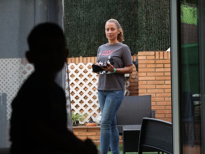 Liam en primer plano en sombra y su madre, Yolanda Montero, en el jardín de su casa en Móstoles, con el medidor de azúcar en la mano.