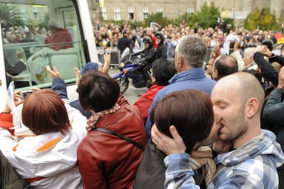 A gay couple kiss one another as Pope Benedict XVI travels through the streets of Santiago.